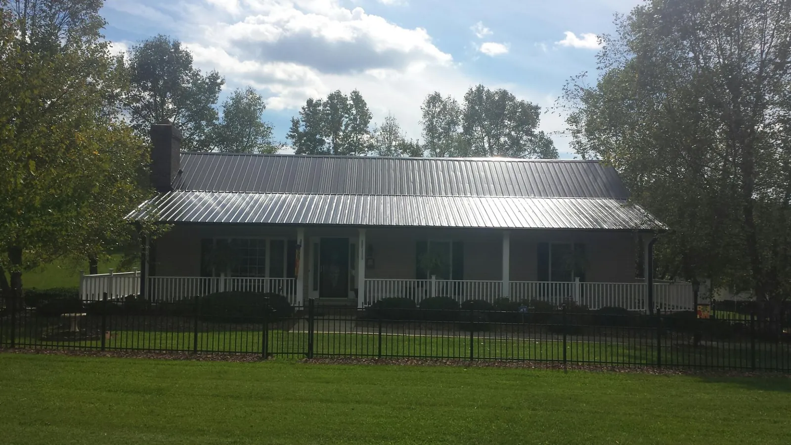 Gray metal roof on a brick ranch with a full width front porch — Gutter Guard Installation work by our crew in Colfax