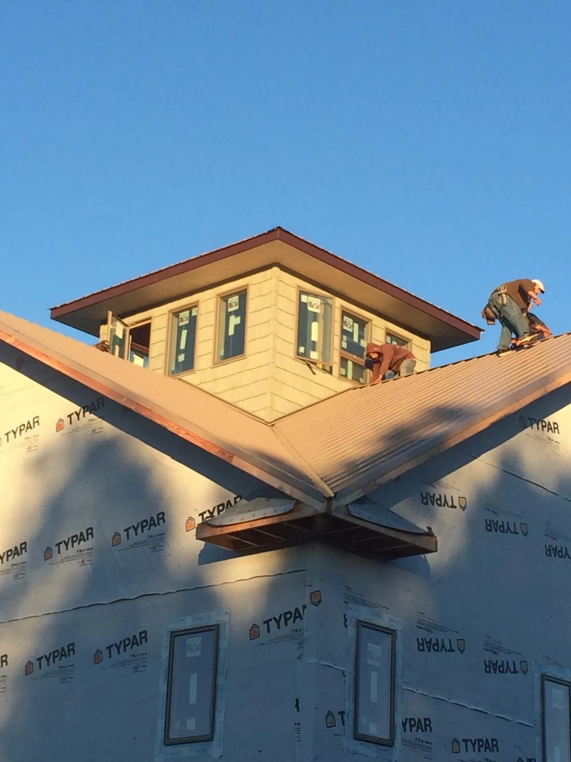 Roofers working around a rooftop cupola on a new metal roof at sunset — Roof Waterproofing in Colfax by Roofing Brothers